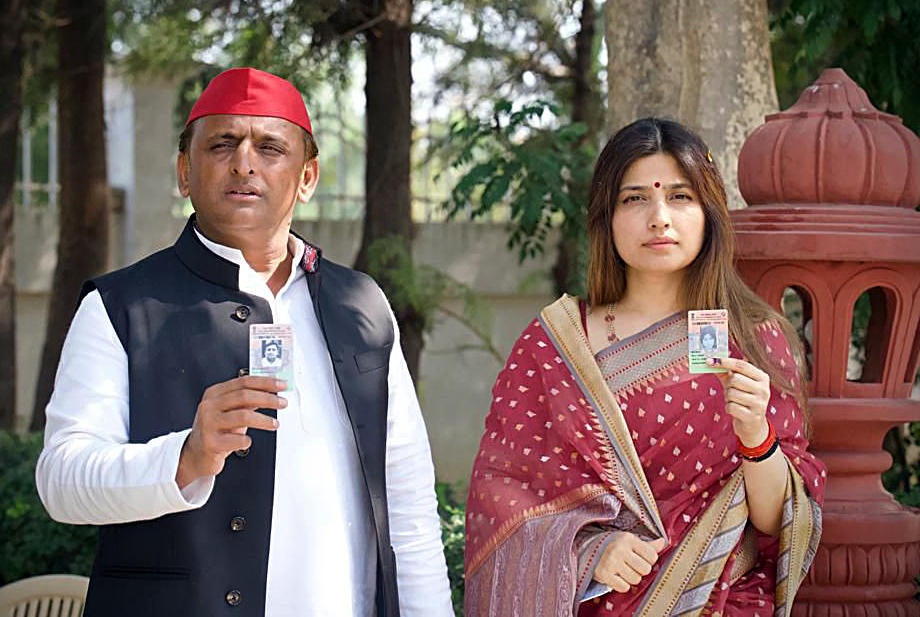 Akhilesh Yadav and his wife Dimple Yadav show their Voter ID cards after casting votes