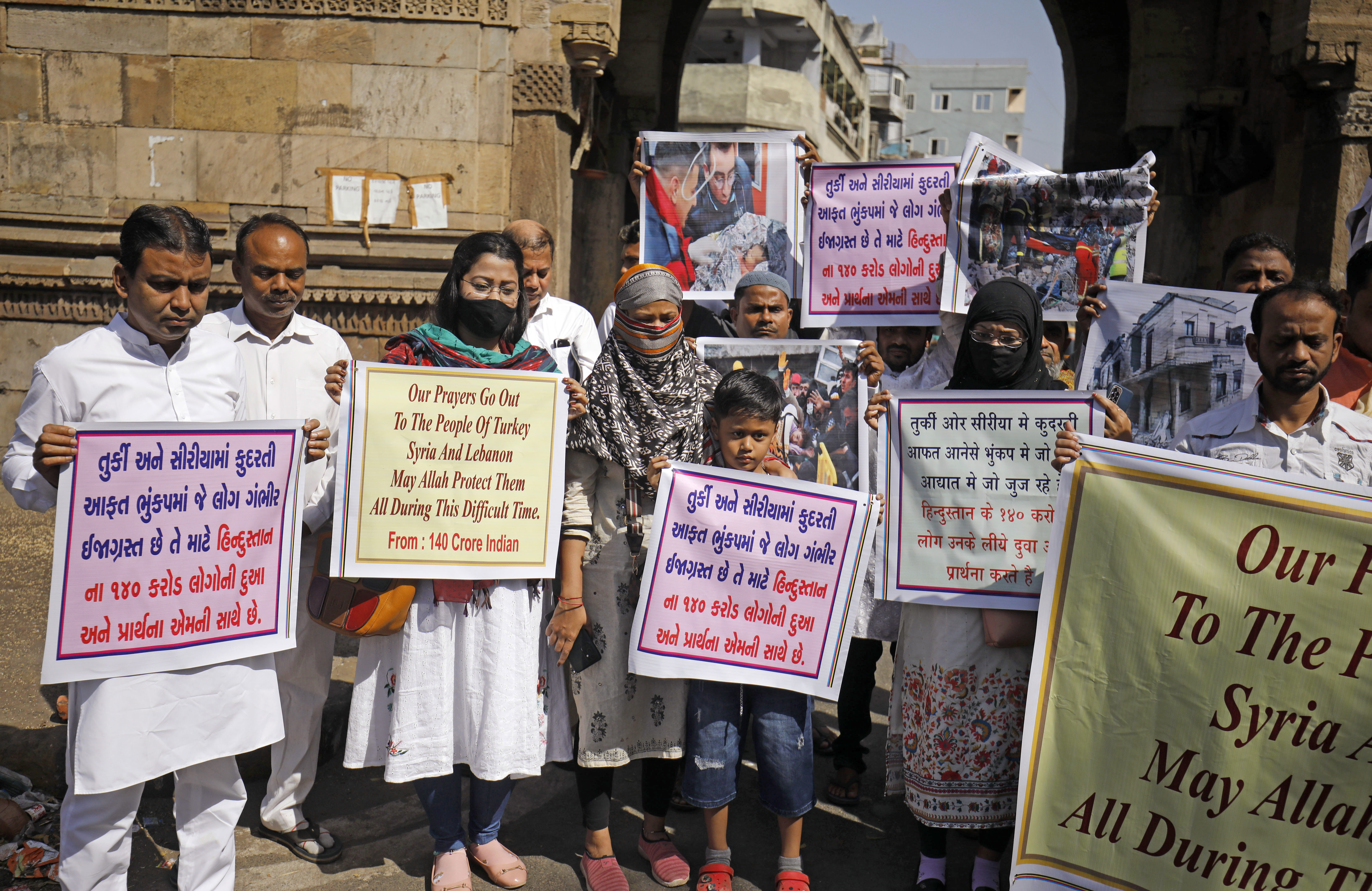 People hold placards to pay tribute to those who died during the earthquakes in Syria and Turkey