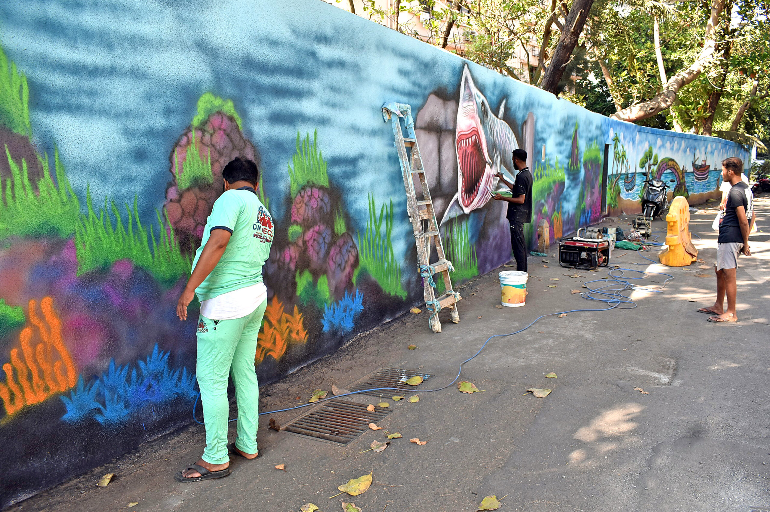 Artists paint an under sea landscape on the wall near Narayan Dabholkar Road