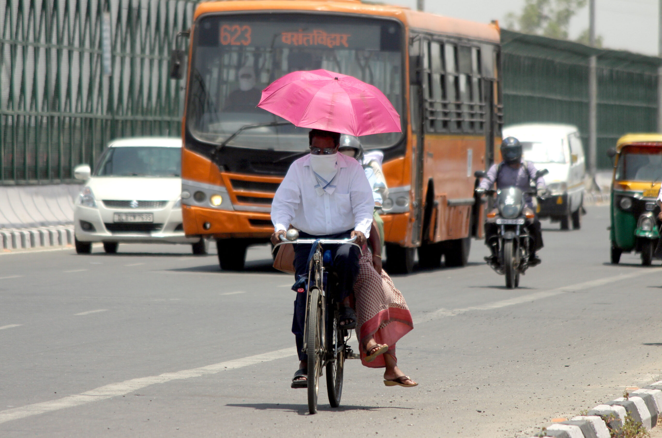 A man rides a bicycle as a woman holds an umbrella during the heatwave in New Delhi.