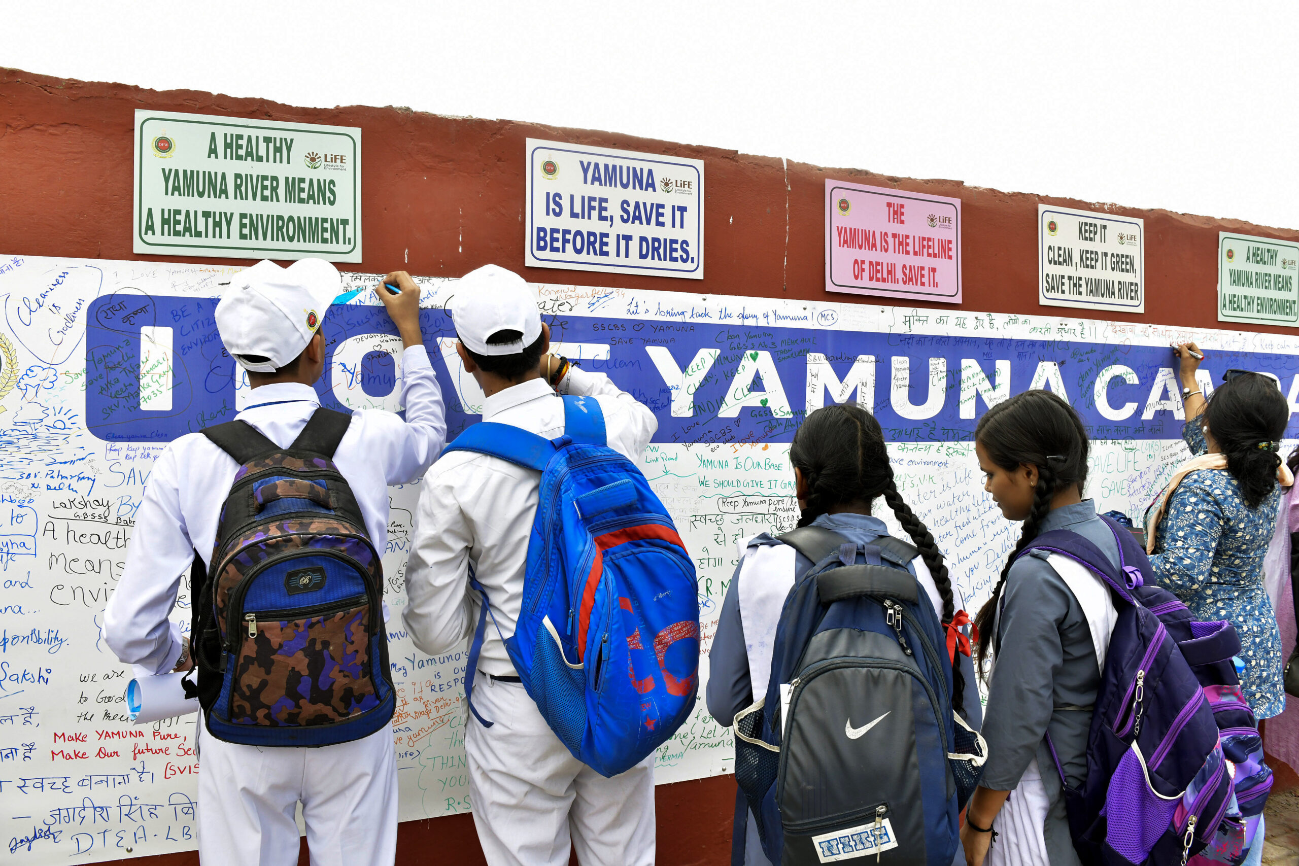 Delhi Government school students write on the signature board during the launch of the ‘I Love Yamuna’ campaign