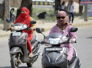 Commuters use scarves to shield themselves from the heat on a hot summer day