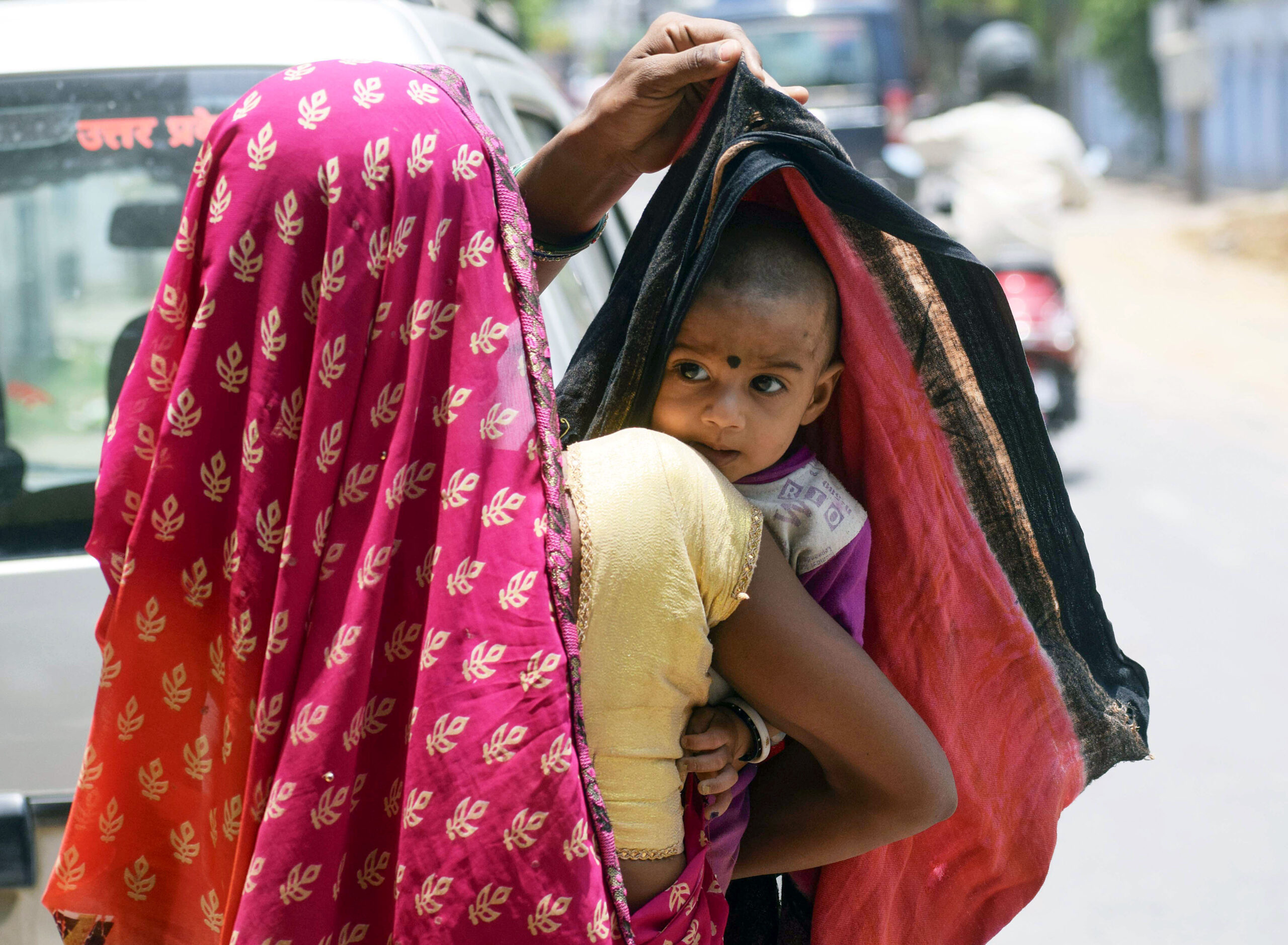 Woman covers head of her child to protect from sun on a hot summer day