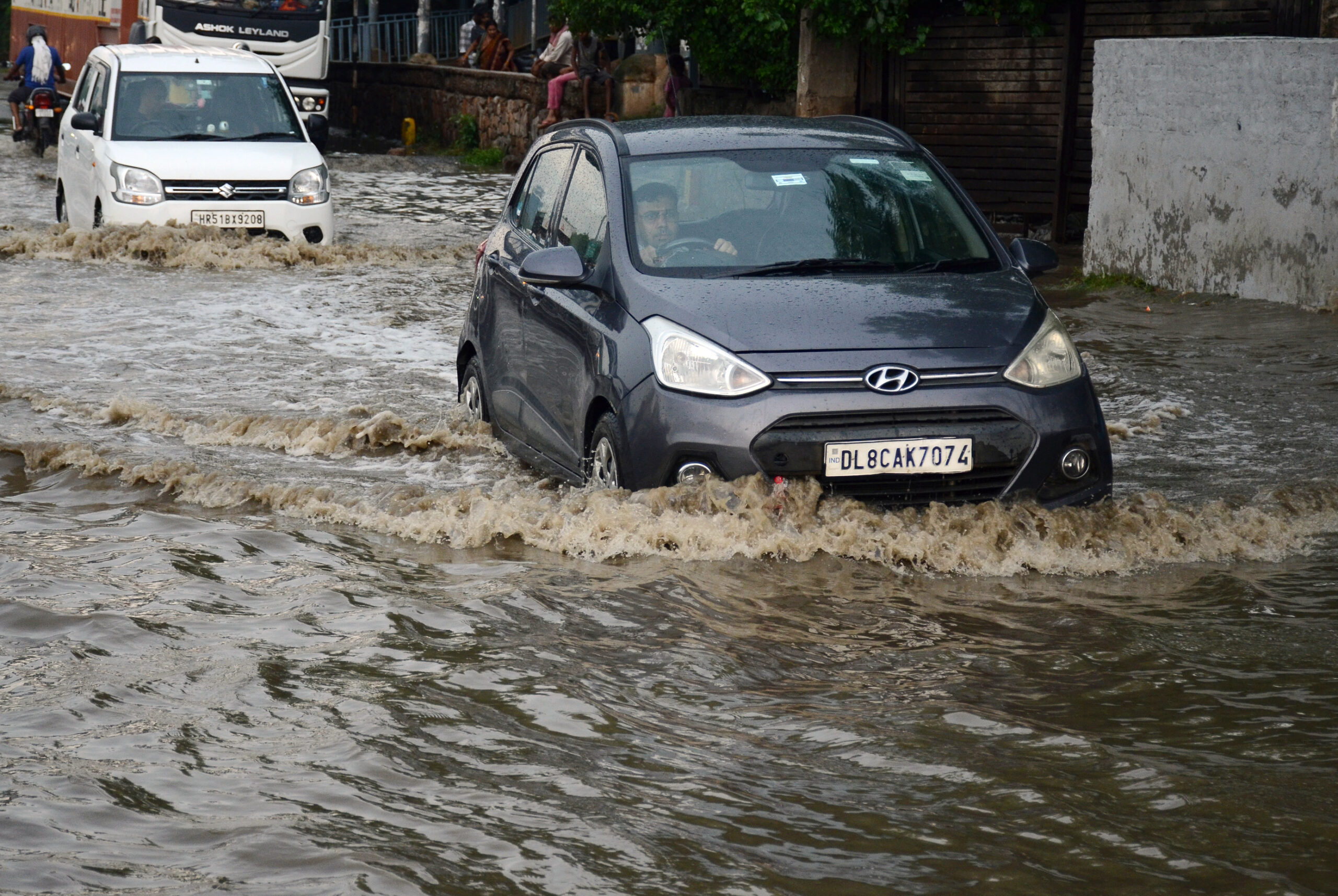 Commuters wade through a waterlogged road after rainfall